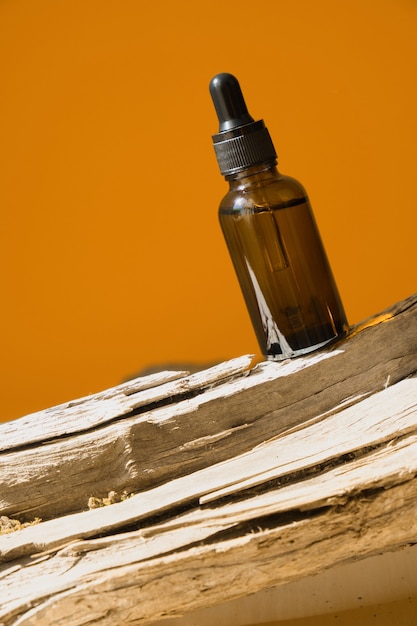 Glass cosmetic bottle with a dropper on a log