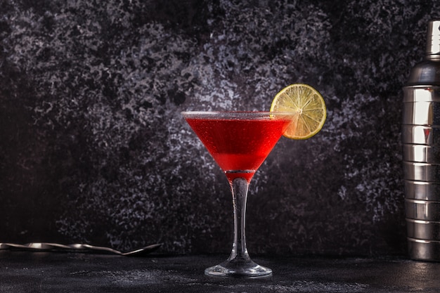 Glass of cosmopolitan cocktail decorated with lime