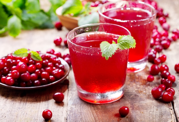 Bicchiere di succo di mirtillo rosso con frutti di bosco freschi sulla tavola di legno