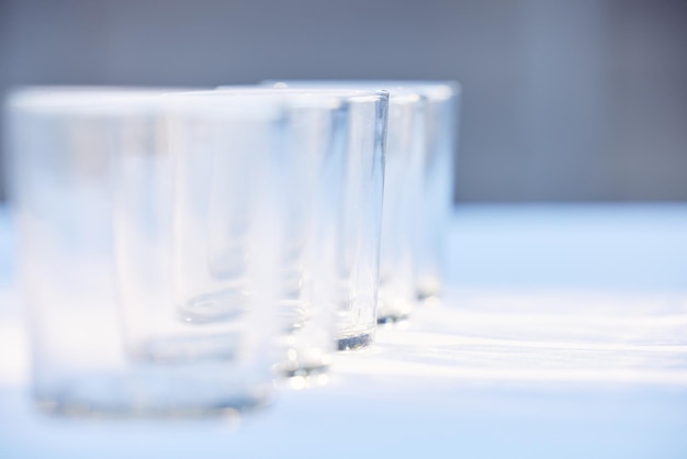 Glass crockery and mockup with a row of drinking glasses on a table in a studio or restaurant for fine dining Space glassware and drinks with a group of cups in a line for a beverage while dining