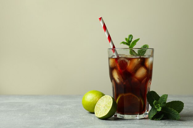 Glass of Cuba Libre and ingredients on gray table