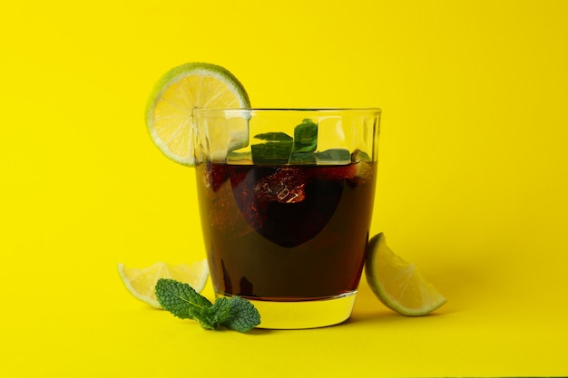 Glass of cuba libre on yellow wall