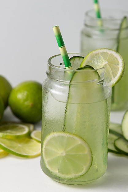 Glass of cucumber and lime drink on white table