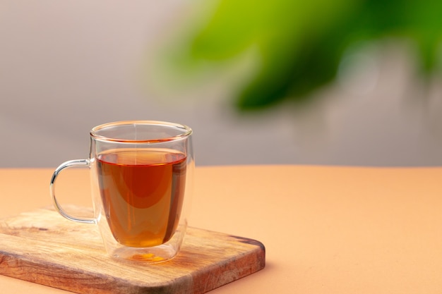 Glass cup of black tea on beige table