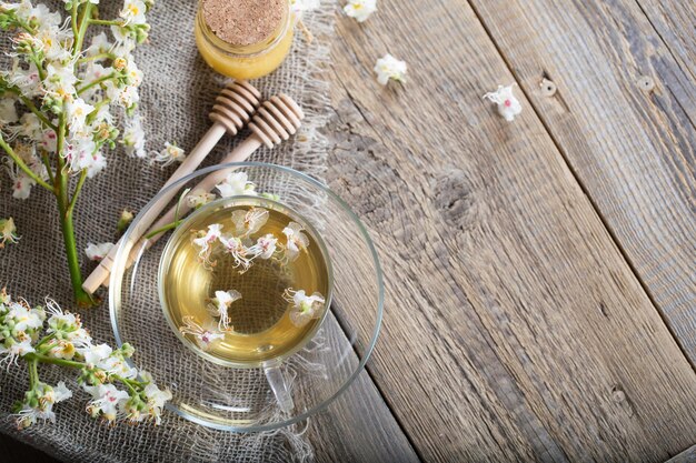 Photo glass cup of chestnut tea. honey and chestnut blossoms in the background.