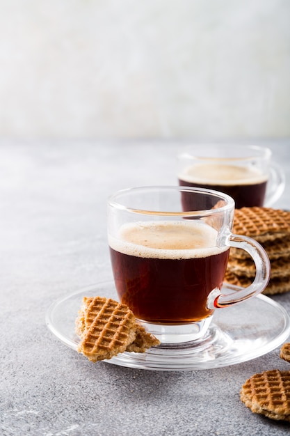 Glass cup of coffee with syrupwaffles cookies