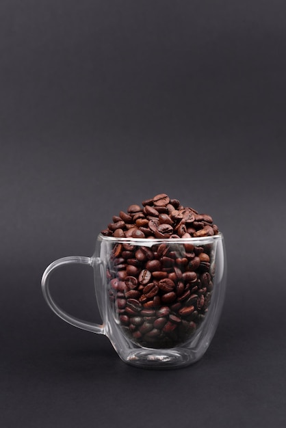 Glass cup full of bean coffee isolated on black background Coffee Maker