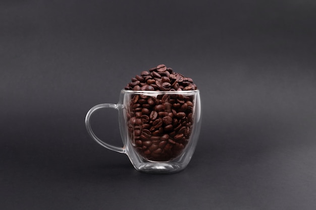 Glass cup full of bean coffee isolated on black background Coffee Maker