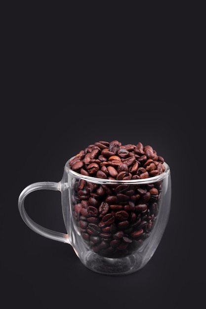 Glass cup full of bean coffee isolated on black background