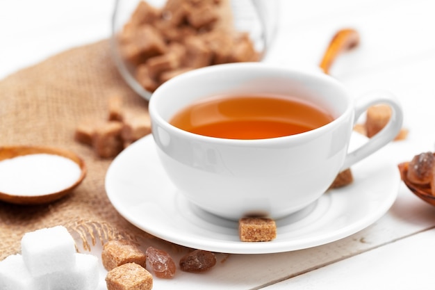 Glass cup of hot tea with sugar on the table