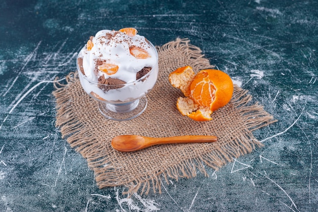 Glass cup of ice cream decorated with fruits on marble surface .