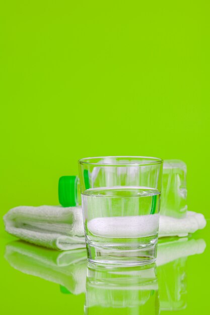 Glass cup of mineral water on green background