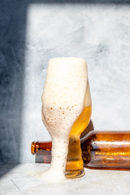 Glass cup served with IPA beer and a bottle and a can at the bottom