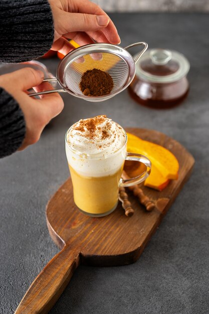 A glass cup of spicy pumpkin cappuccino on grey surface