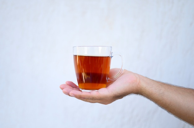 glass cup of tea in the male hand