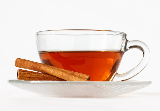 Glass cup of tea with cinnamon sticks.