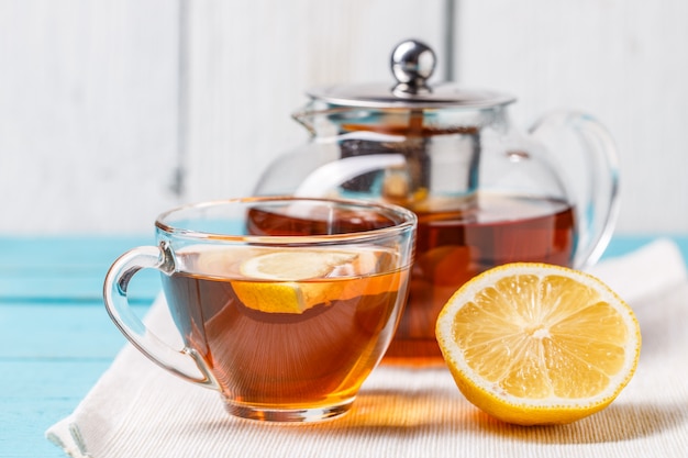 Photo glass cup of tea with lemon and glass teapot.