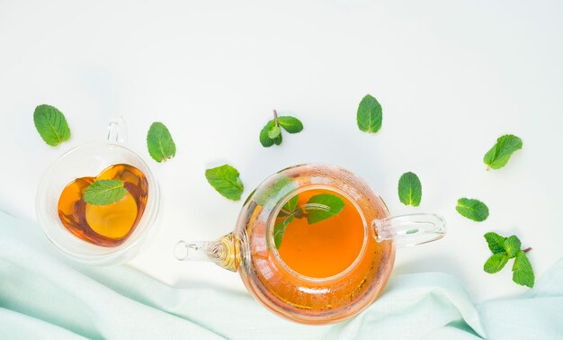 Photo glass cup and teapot with mint tea on a light background