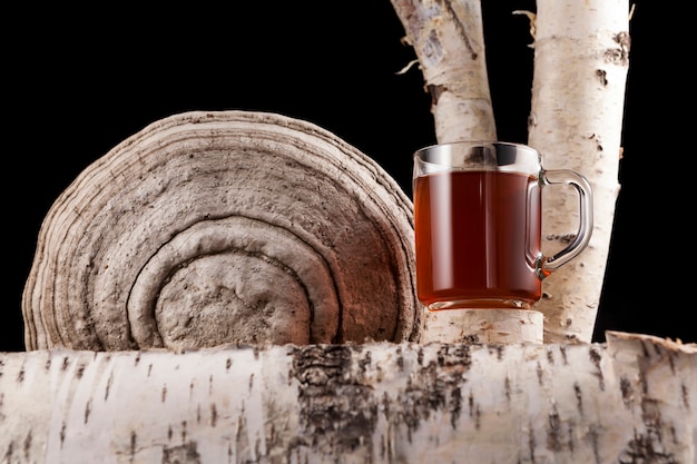 Glass cup with a healing infusion of chaga birch mushroom. Tea or coffee with chaga mushrooms.