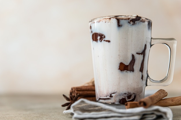 Glass cup with hot chocolate or cocoa drink and cinnamon sticks with anise