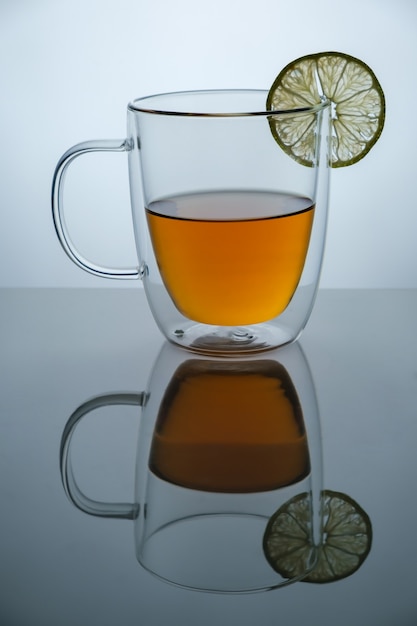 Glass cup with hot tea and lemon on black mirror surface, studio advertising shot, copy space