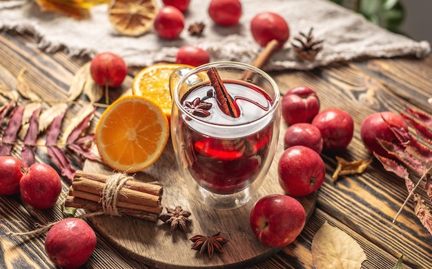 Glass cup with mulled wine decorated with cinnamon star anise and orange on a wooden table Concept of a traditional warming beverage