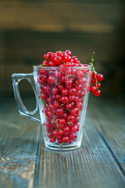 Glass cup with red currant. Wooden background. 