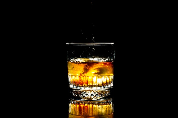 Glass cup with whiskey on a black background