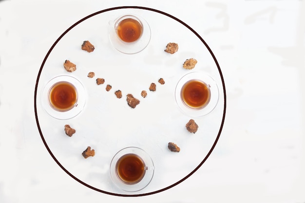 Glass cups of coffee from chaga and pieces of chaga in the shape of a clock on a white background