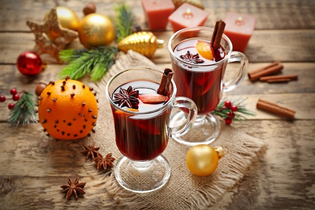 Glass cups of delicious mulled wine with Christmas decor on sackcloth