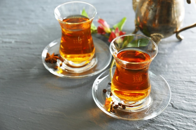 Glass cups of tea and teapot with cinnamon and lemon on the table