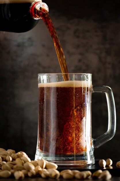 Glass of dark beer with hops around on a dark background