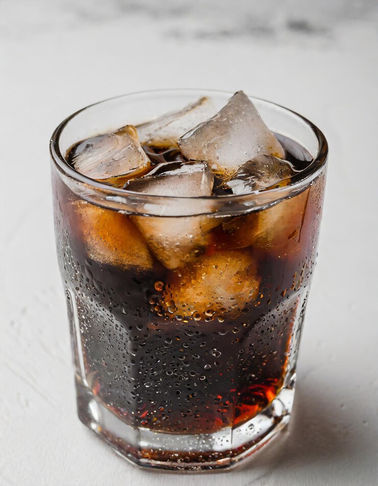 Photo glass of dark fizzy drink with ice cubes cola or soda beverage on light background summer cocktail