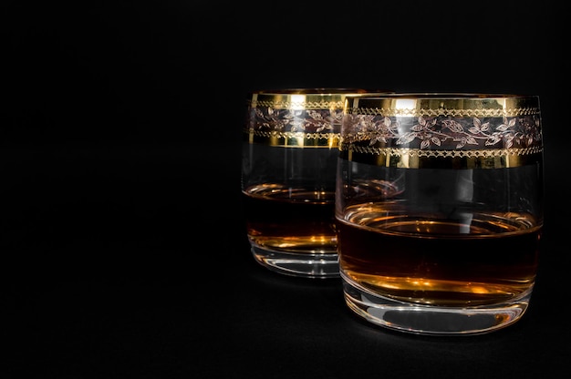 黒の背景に分離された濃い赤のウイスキーブランデーまたはxAbourbonのガラスアルコールのクローズアップ写真