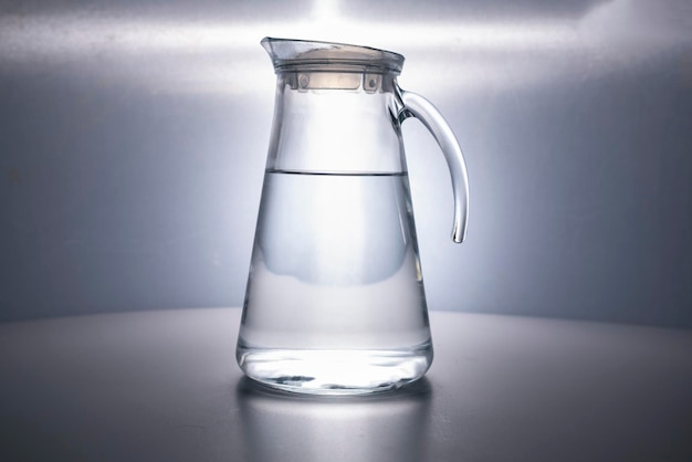 Foto decanter in vetro riempito con acqua potabile pulita splendidamente illuminato su sfondo grigio pubblicità dell'acqua brocca l'acqua è vita spazio per il testo copyspace nessun soggetto riprese