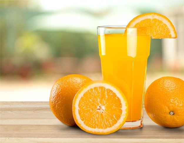 Glass of delicious orange juice on table background