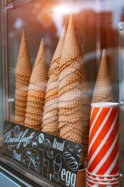 Glass display case in an ice cream parlor cones with many cones for ice cream cornets. Refreshing summer food in the heat street fast food to take away