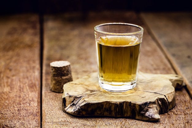 Glass of distilled alcoholic beverage on wooden background with copy space for text. Call for rum or cachaÃ§a