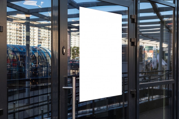 Glass door of ofiice building with white empty panel