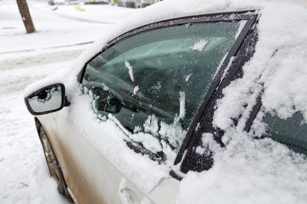 運転席の車のドアのガラスは溶ける雪で覆われています。冬の車