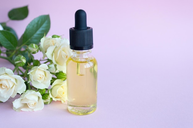 Foto flacone contagocce in vetro cura cosmetica spa tea rose olio essenziale ramo di fiori bianchi