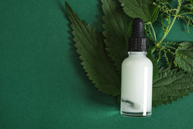 Glass dropper bottle of nettle oil or serum and nettle leaves