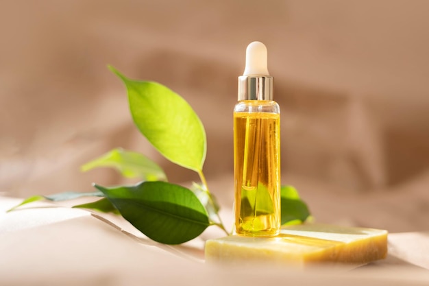 Glass dropper bottle with cosmetic oil essential or serum soap and green leaves on paper background