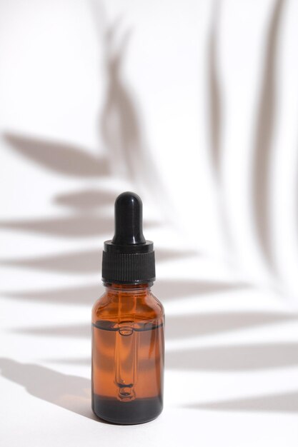 Glass dropper bottle with shadow palm leaves Cosmetic container mockup