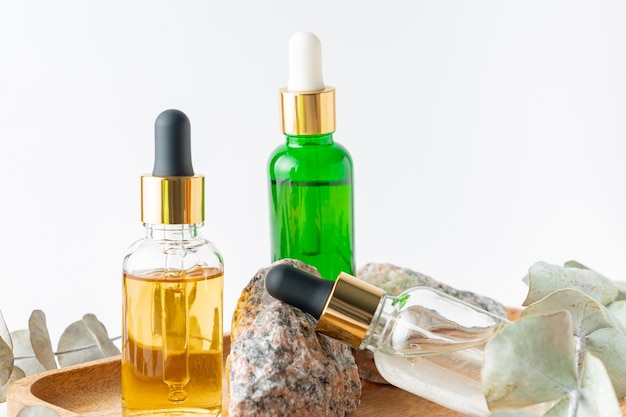 Glass dropper bottles with cosmetic oil essential oil or serum on stone stand with branch eucalyptus Herbal homeopathic products Natural organic spa cosmetics