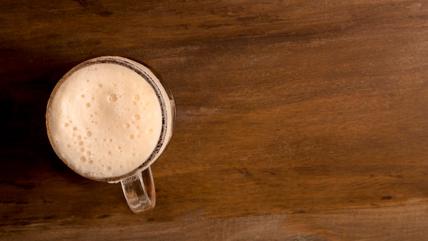 Glass of foamy beer on wooden table 