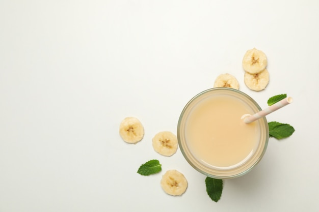 Glass of fresh banana juice on white