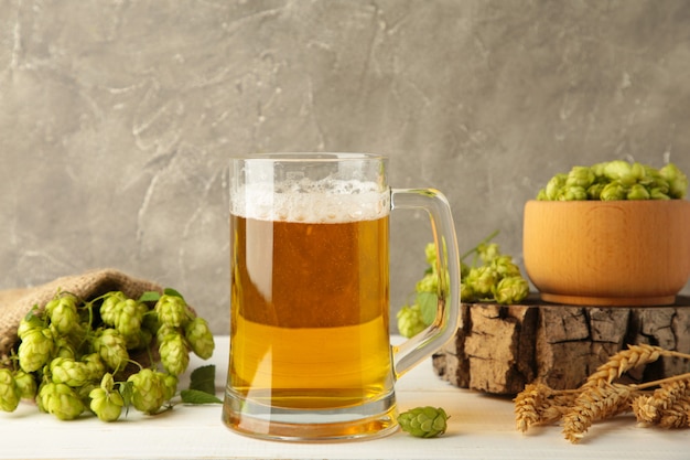 Glass of fresh beer with green hops and wheat on a grey background. Top view