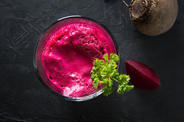 Glass of fresh beetroot juice garnish parsley on black.