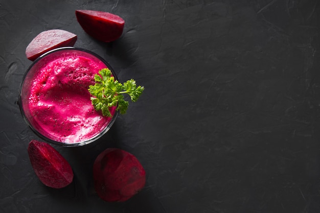 Glass of fresh beetroot juice garnish parsley on black.